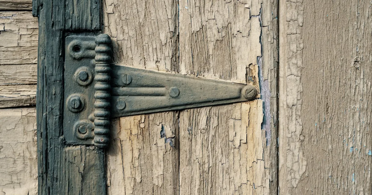 Dobradiça de ferro em uma porta de madeira antiga